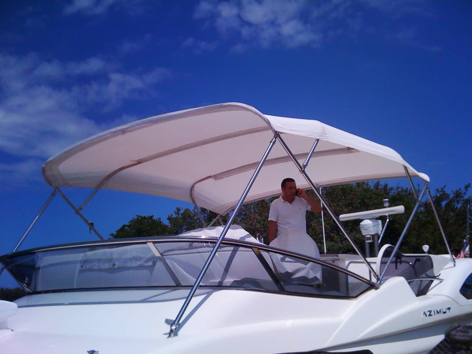Oscar Sr technician fabrication of custom white canvas Bimini top and flybridge upholstery on an Azimut yacht.
